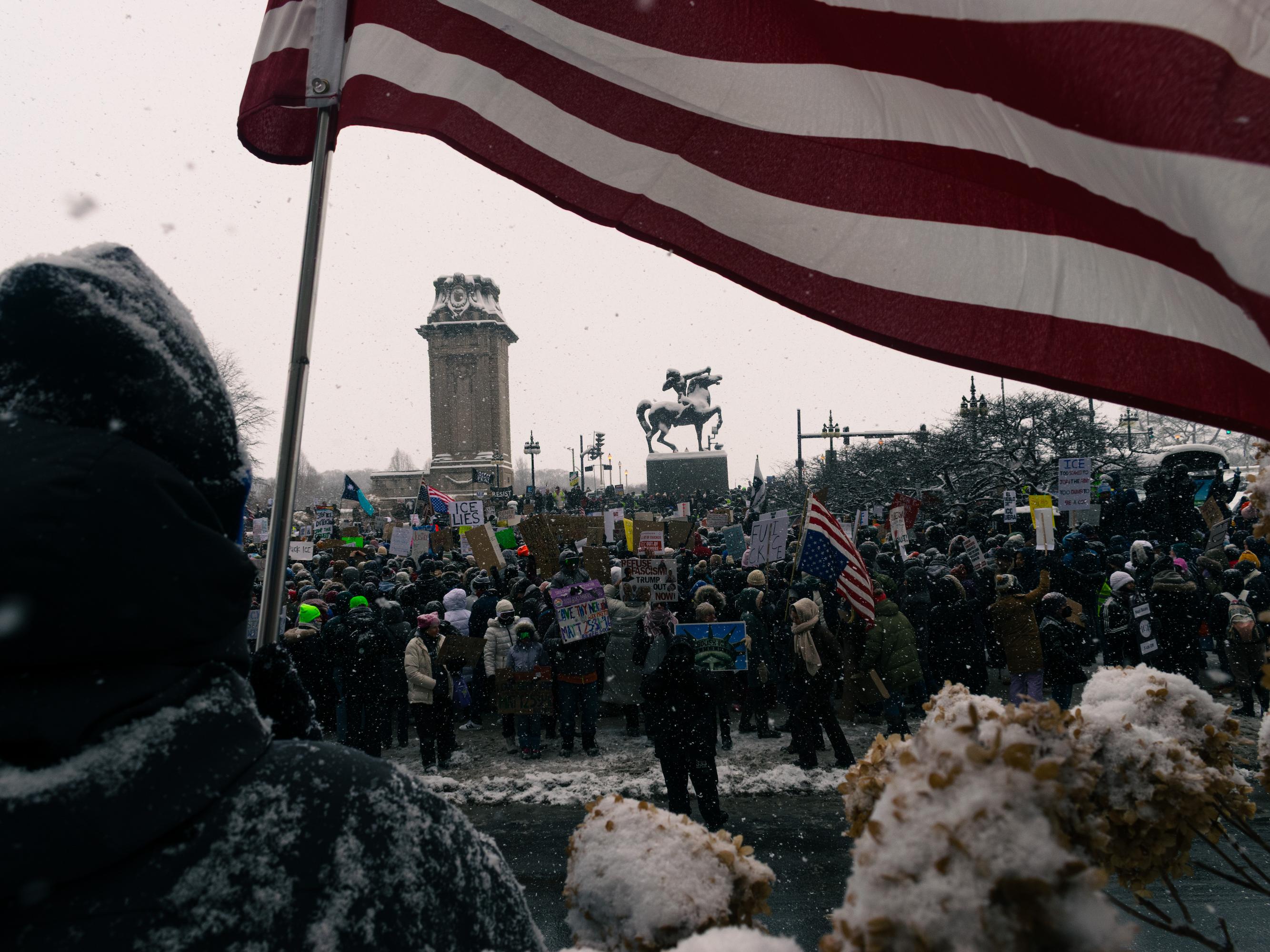 Picture of a man with a flag standing infront of a crowd of protesters on January 25th, 2026.